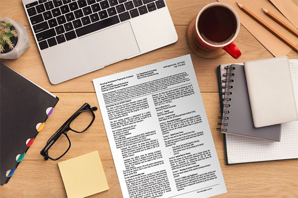 Aerial view of a desk showing papers, notebooks, coffee, glasses, laptop, and succulent