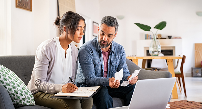 Man and woman looking over paystubs near a computer