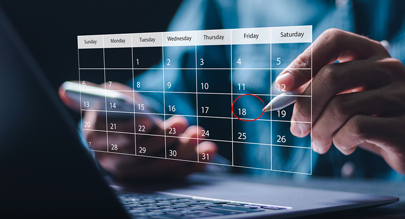 Person selecting a calendar date while using a laptop and smartphone
