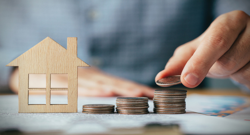 stacking coins next to a house to insinuate junk fees, a key component of the initiative